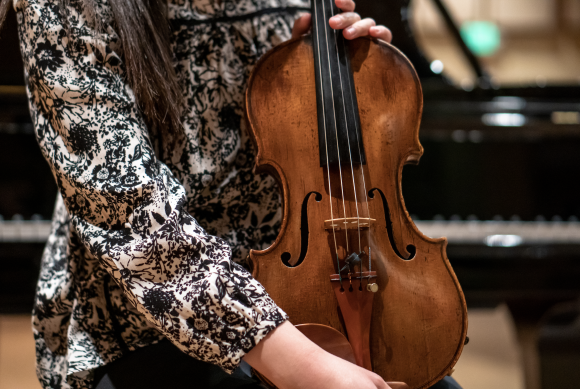 A close up of Liu holding the violin.
