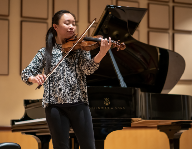 Danielle Liu plays the violin in front of the piano in Salmon Recital Hall