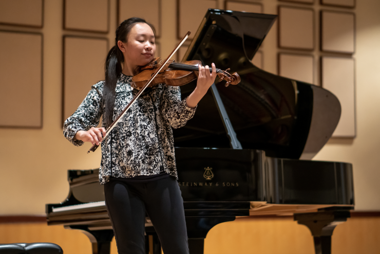 Danielle Liu plays the violin in front of the piano in Salmon Recital Hall