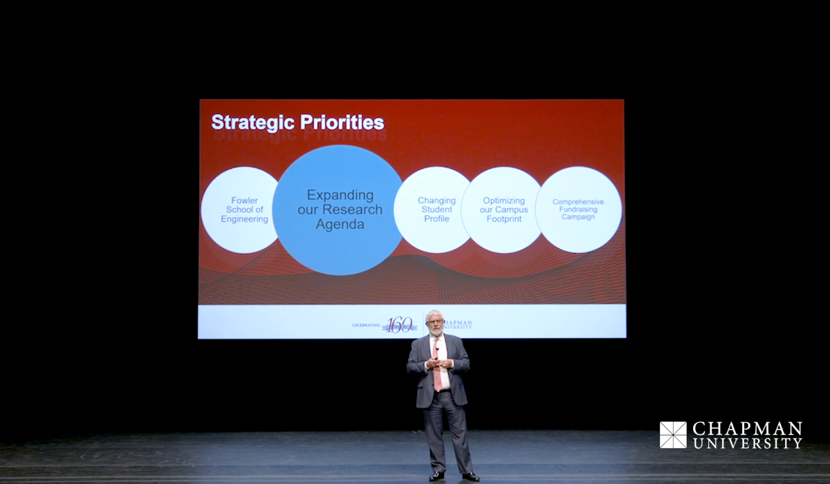 president daniele struppa on stage with screen reading "strategic priorities" behind him