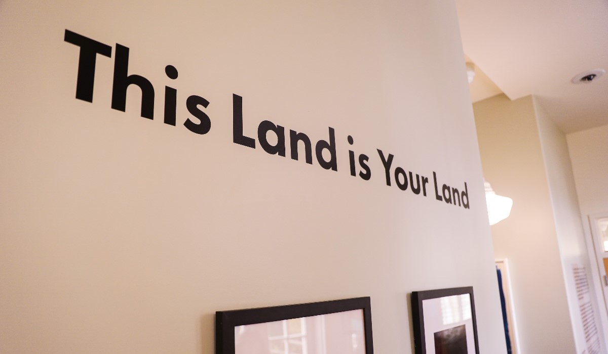 Wall displayed with art exhibition title This Land is Your Land.