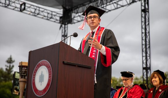 phillip goodrich at podium in cap and gown