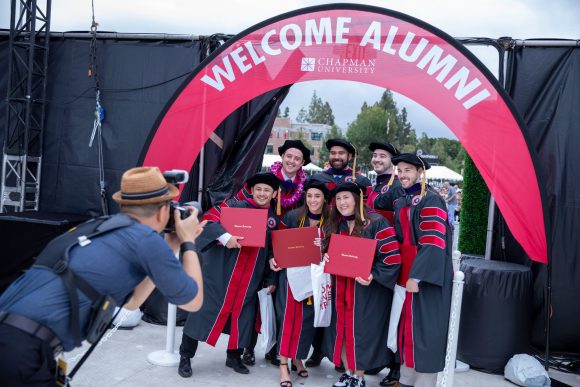 grads with diplomas under welcome alumni banner