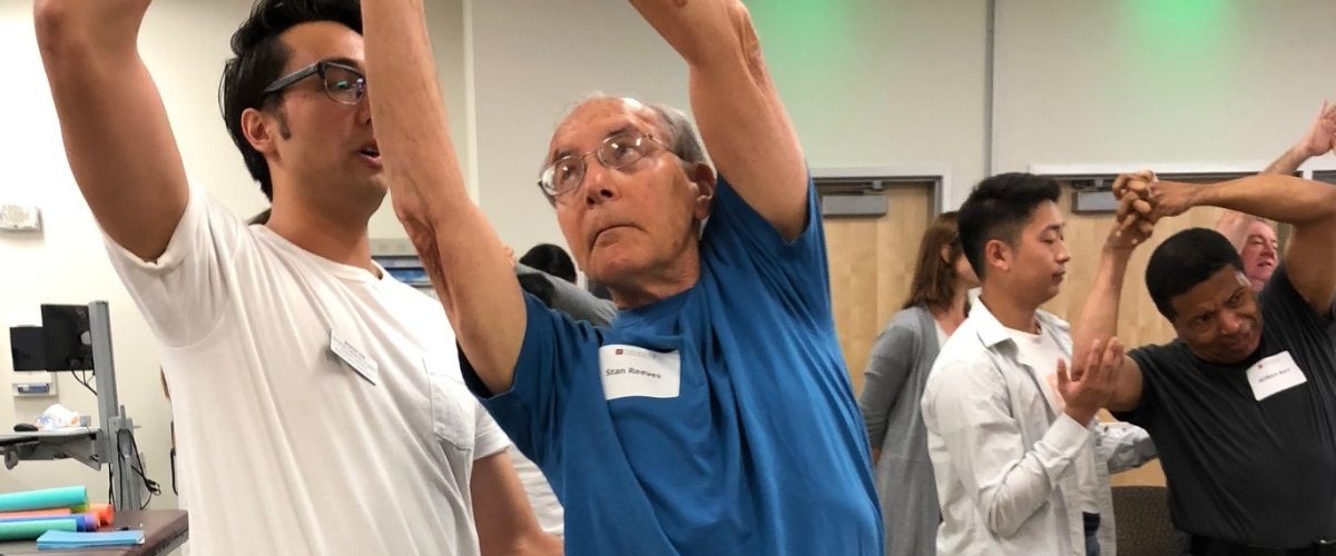 male patient raises arms overhead assisted by physical therapist