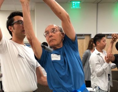 male patient raises arms overhead assisted by physical therapist
