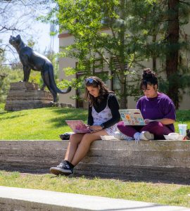 two female students with computers studying outside on chapman campus