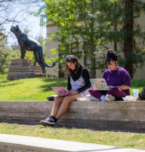 two female students with computers studying outside on chapman campus