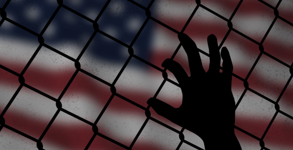 a hand grasps at a chain link fence with the American flag in the background