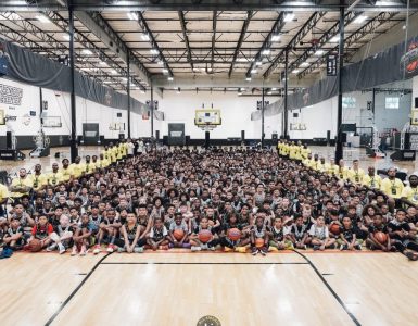 group shot of hundreds of kids and dozens of staff on floor of open gym