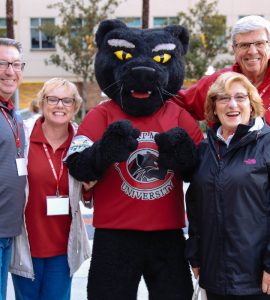 Pete the Panther mascot stands with two men and two women in Chapman gear on Chapman campus