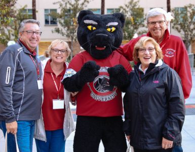 Pete the Panther mascot stands with two men and two women in Chapman gear on Chapman campus