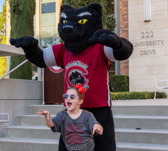 Pete the Panther mascot and young girl in chapman t-shirt make "paws up" gesture with fierce face