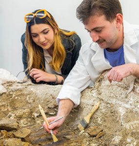 Chapman students work with a dinosaur fossil in the lab.