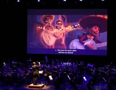 concert stage with scene from Coco playing on screen over a live orchestra