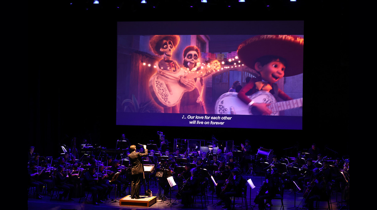concert stage with scene from Coco playing on screen over a live orchestra