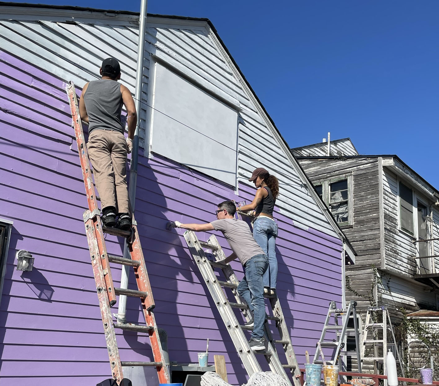 3 students paint a purple house in New Orleans