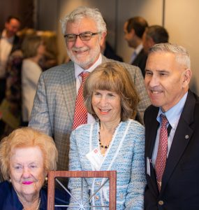 Sandy Fainbarg, left, with Nancy and Irv Chase and President Struppa pose for a photo holding a gift of a Chapman window sculpture.