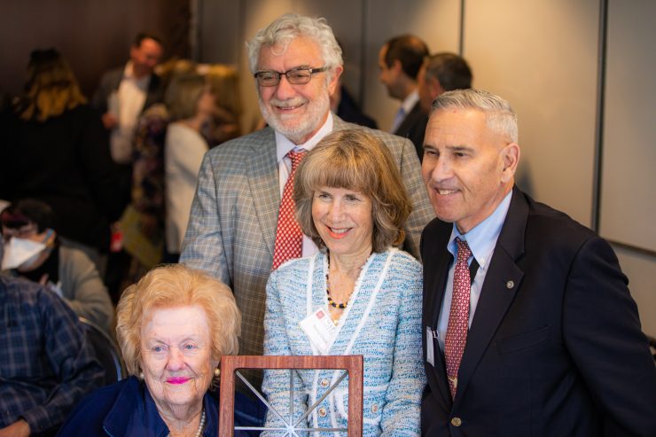 Sandy Fainbarg, left, with Nancy and Irv Chase and President Struppa pose for a photo holding a gift of a Chapman window sculpture.