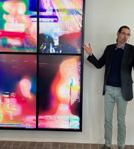 Daniel Canogar standing next to Pareidolia, an artwork consiting of moving images on four video screens