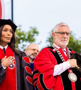 angela basset and daniela struppa in academic regalia holding hands over their hearts