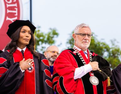 angela basset and daniela struppa in academic regalia holding hands over their hearts