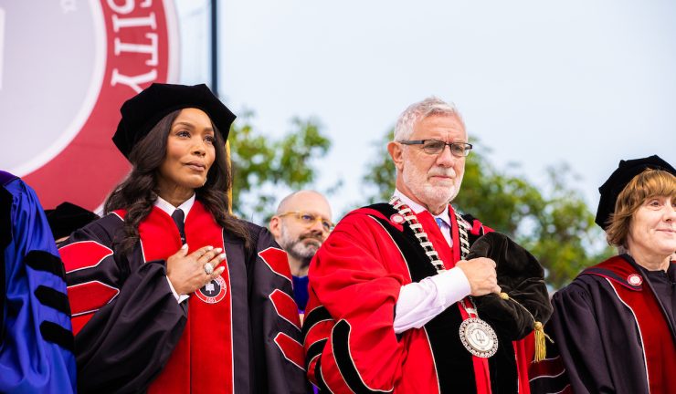 angela basset and daniela struppa in academic regalia holding hands over their hearts