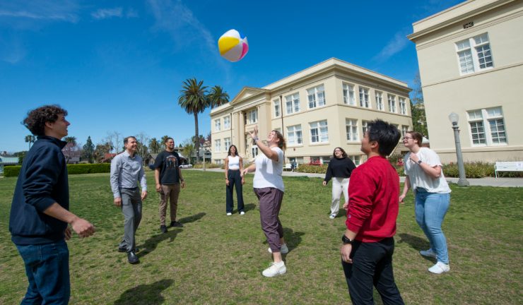 group of students hit a beachball in the air on chapman's memorial lawn
