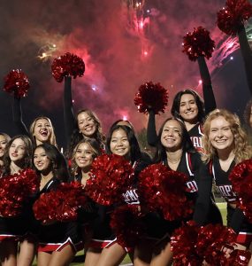 cheerleaders pose with fireworks overhead