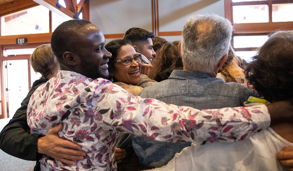 group of people hugging - one woman smiles at camera