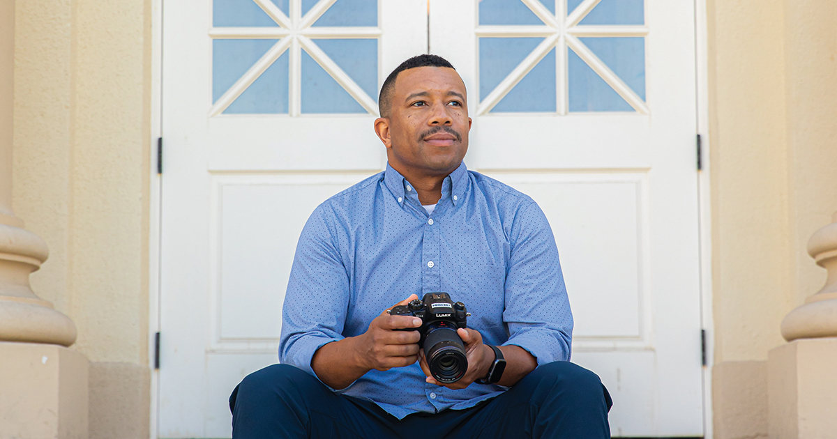 Quaylan Allen sits on steps of Chapman's Memorial Hall holding a camera