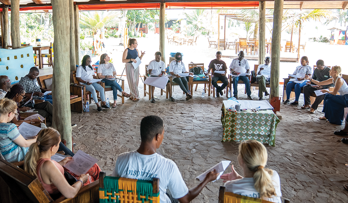 group of people in open tent, sitting in a circle