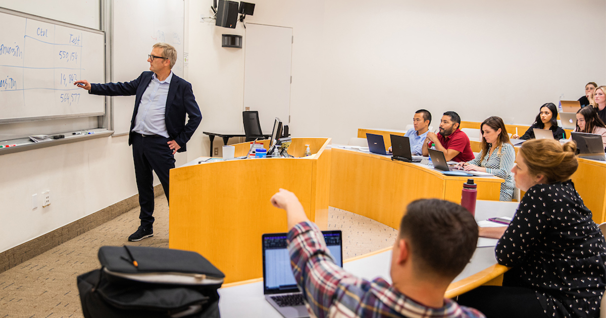 professor pointing at whiteboard in classroom