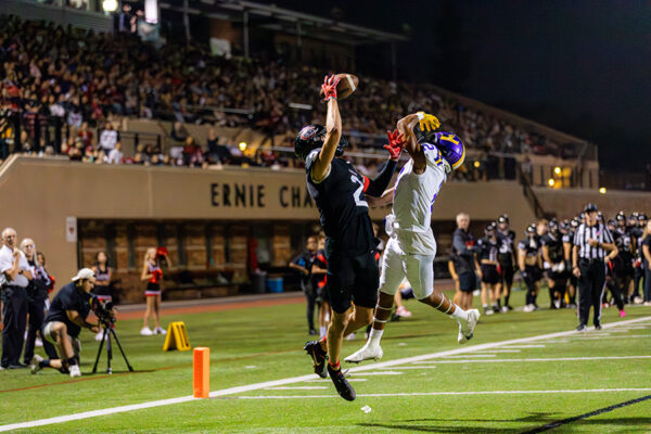 two football players on opposing teams leaping in air