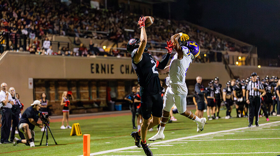 two football players on opposing teams leaping in air