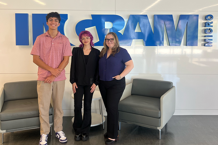 three students in front of inagram micro sign