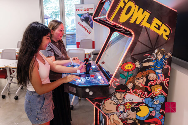 students playing at arcade game with "Fowler" on the side