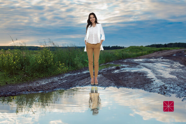 julia boehm standing beside a pond with a reflection of a small child in the water