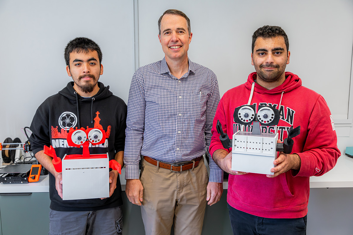 three team members smiling and showing off their camera designs