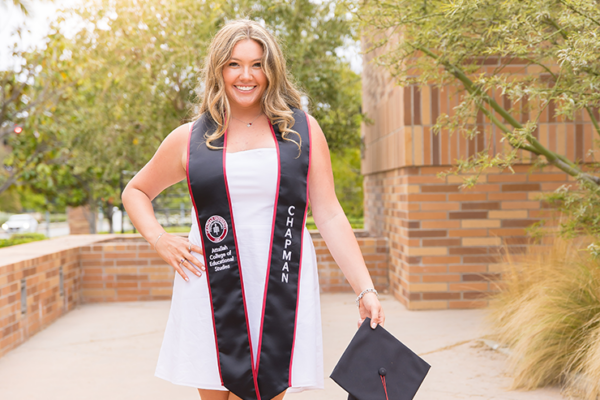 Chapman graduate Kaitlyn Ambriz Holl '25 poses on campus with commencement regalia
