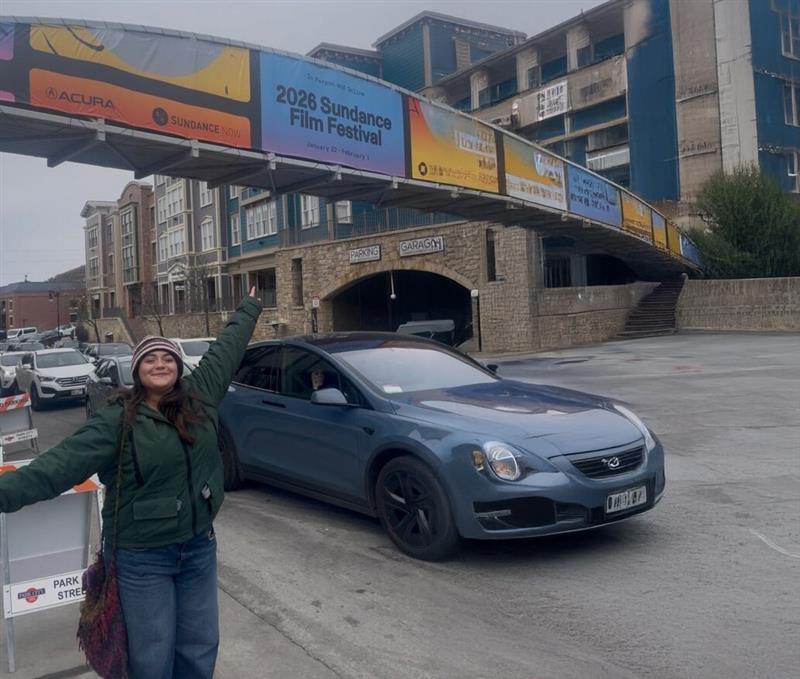 Paige Filipan posing with the Sundance bridge banner on Main Street.