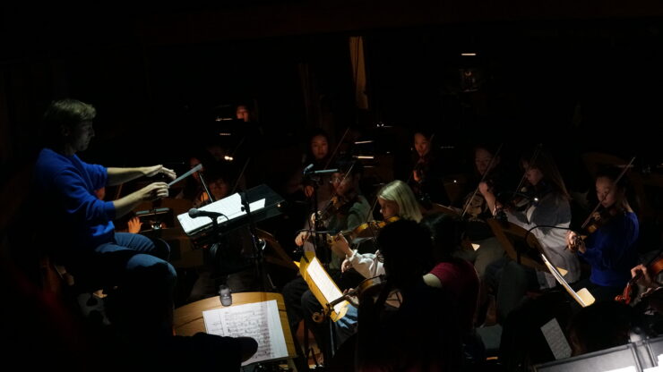 Conductor Danko Druško leads student musicians in the orchestra pit as they perform during a live stage production.