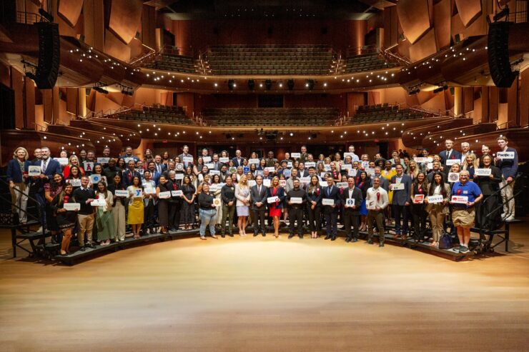 A large group of employer representatives pose for a photo onstage inside Musco Center for the Arts following a recognition ceremony at the State of the University.
