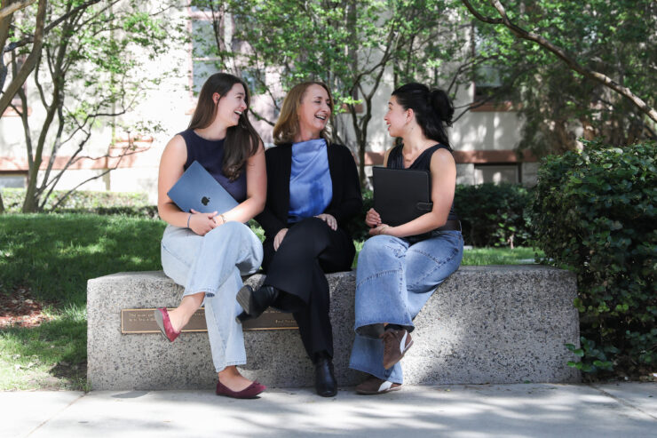 Honors students Ella Bartsch (left) and Ashley Agatep sit outside on a bench with Tara Gruenewald, director of the Honors Program.