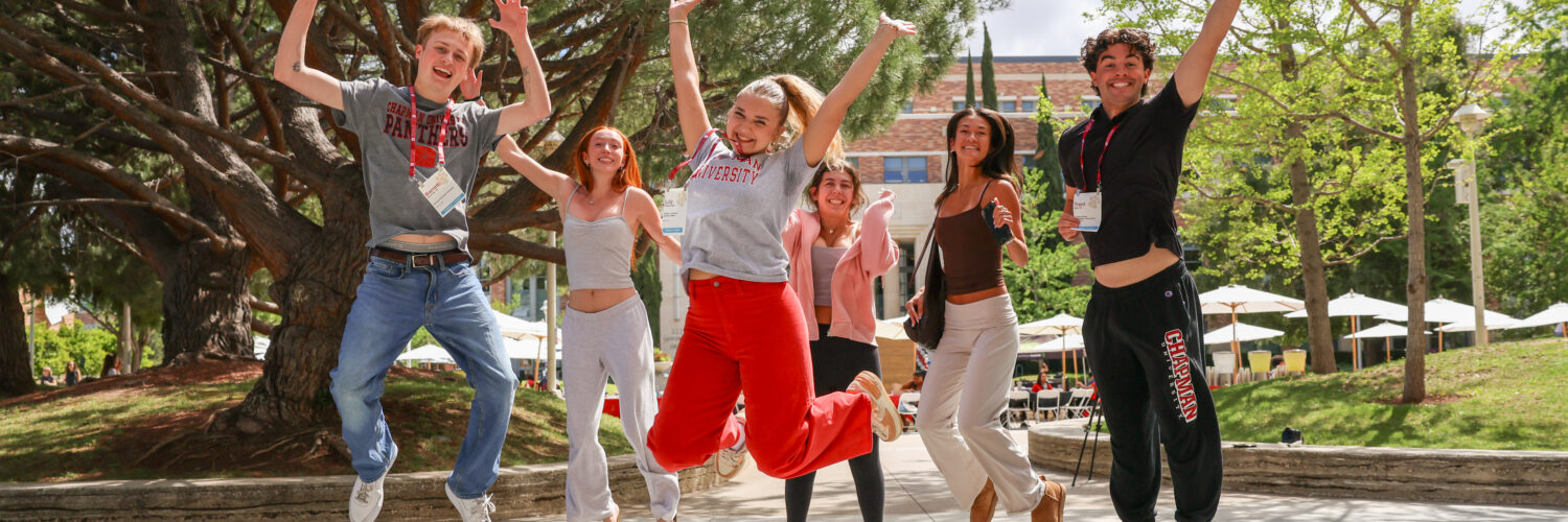 Students wearing Chapman gear happily jump in the air.