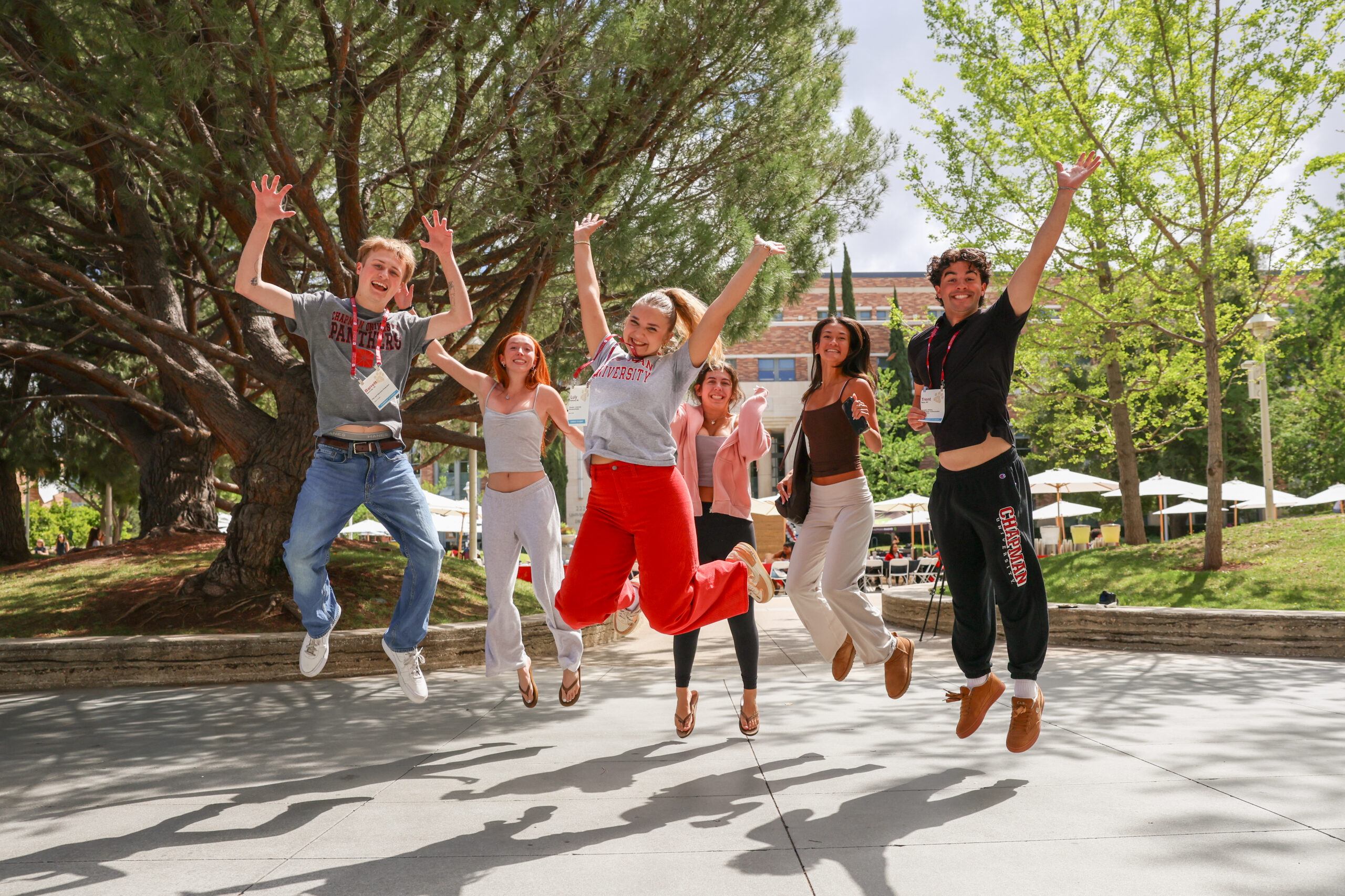 Students wearing Chapman gear happily jump in the air.