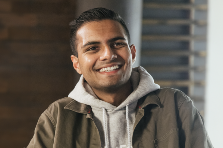 A portrait of a person wearing a jacket and hoodie, overlaid with a “Forbes Under 30 North America 2025” graphic.