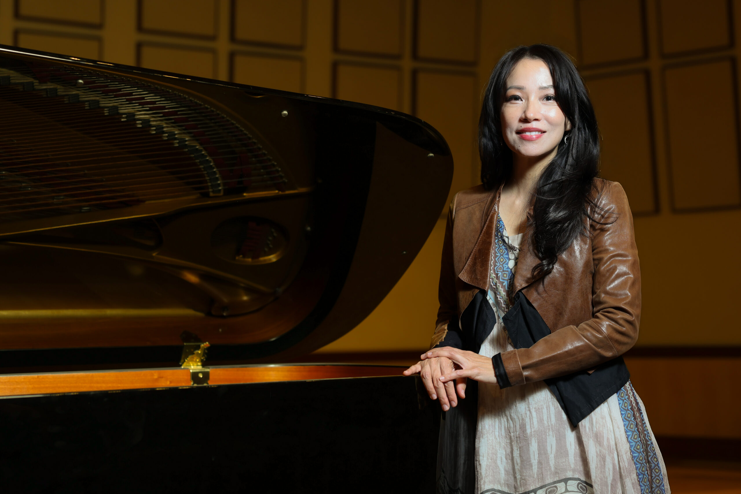 Grace Fong stands beside a grand piano in a performance hall.