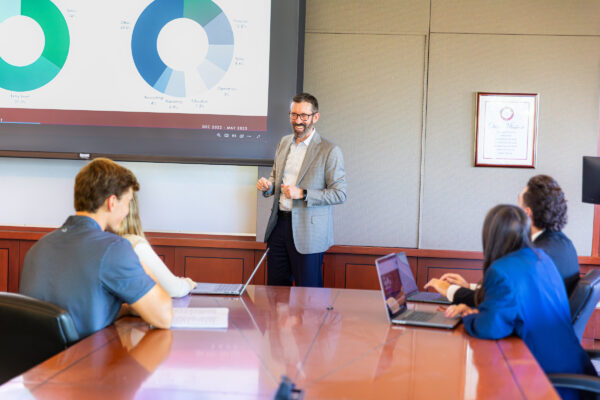 Business professional delivering a boardroom presentation to colleagues during a corporate meeting