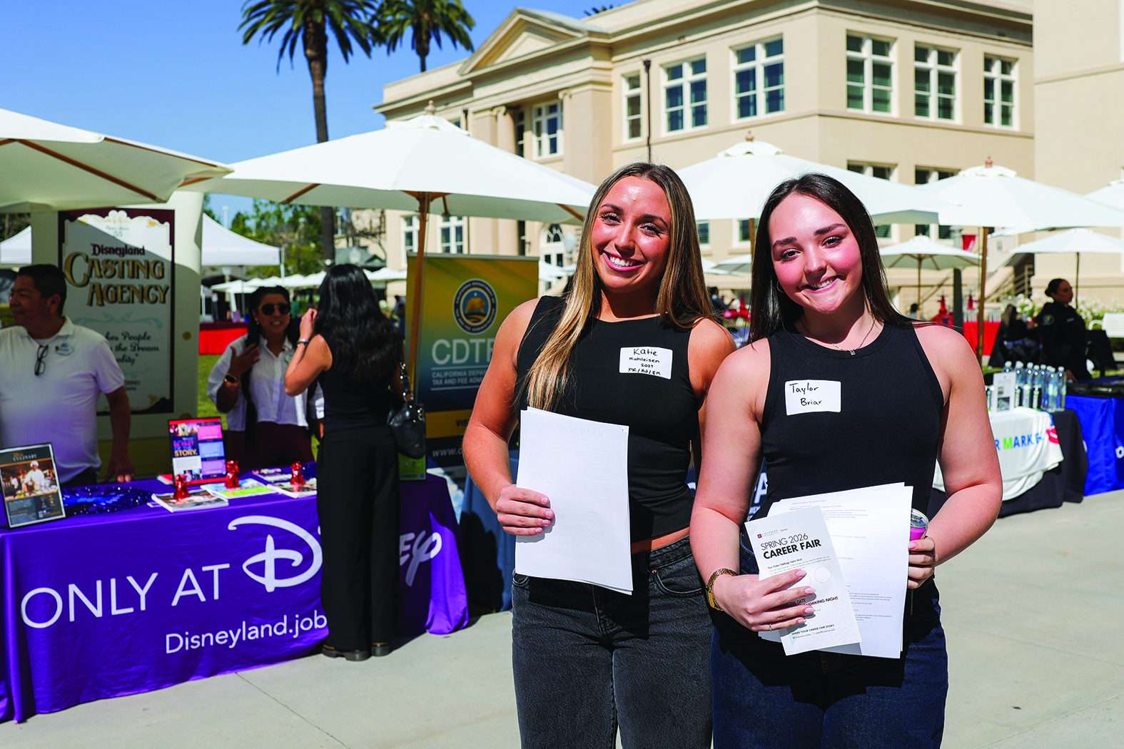 Two students hold their resumes at the career fair.