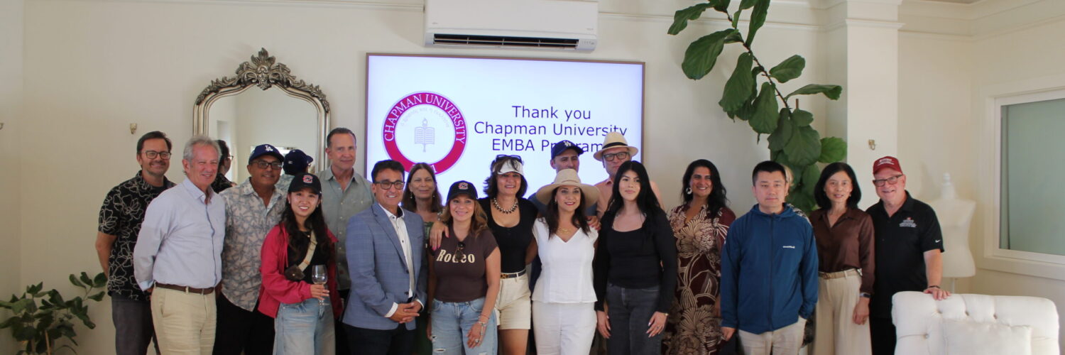 Chapman Executive MBA students and faculty pose for a group photo in front of a screen displaying the Chapman University logo and a thank-you message.